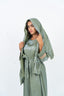 Abaya vert olive avec cape, manches ornées d'incrustations dorées et nœud à la taille.