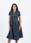 Robe bleu marine à pois blanche avec nœud à la taille.