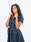 Robe bleu marine à pois blanche avec nœud à la taille.